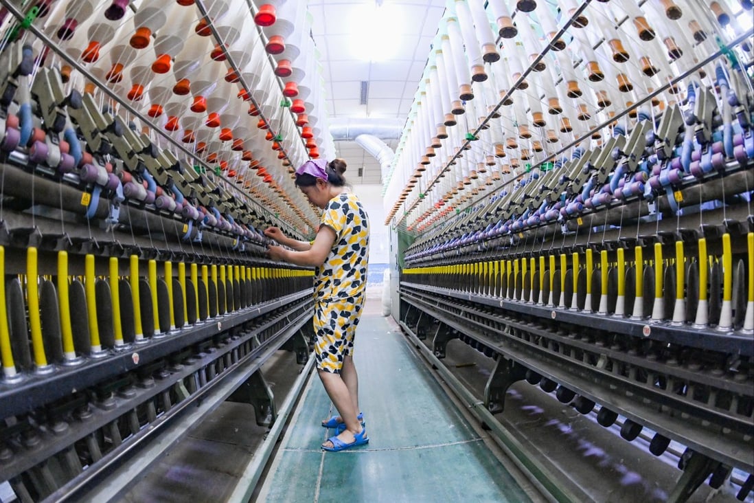 A worker checks a machine at the workshop of a textile enterprise in Qingzhou Economic Development Zone in east China’s Shandong province, on July 27, 2022. Photo: Future Publishing via Getty Images