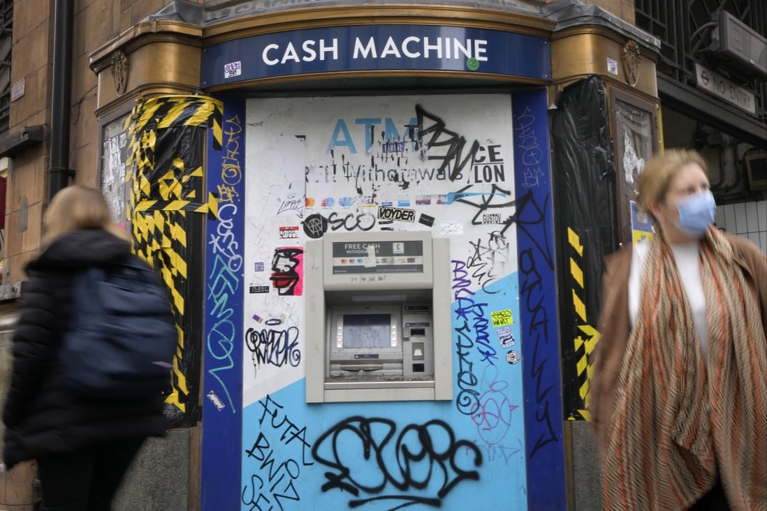 Shoppers pass a graffitied cash machine on Oxford Street in London. Britain’s Prime Minister Liz Truss inherits an ailing economy on the brink of a potentially long recession. Photo: AP 