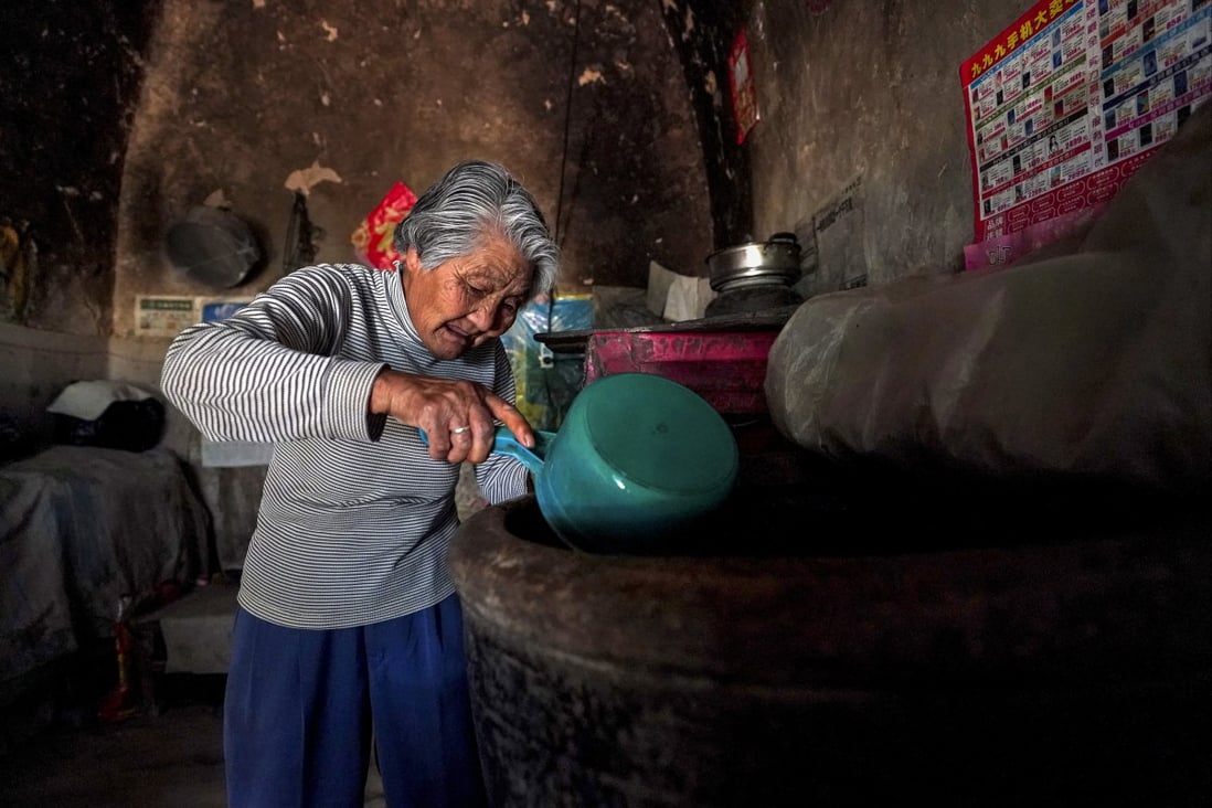 An elderly woman scoops water from a pail at her rural village home in Yicheng county in Shanxi province on July 3, 2019. Photo: Xinhua