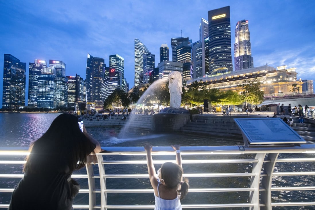 Tourists take pictures of the iconic Merlion statue in Singapore this month. The city state’s population grew this year, as Hong Kong’s continued to decline. Photo: Xinhua