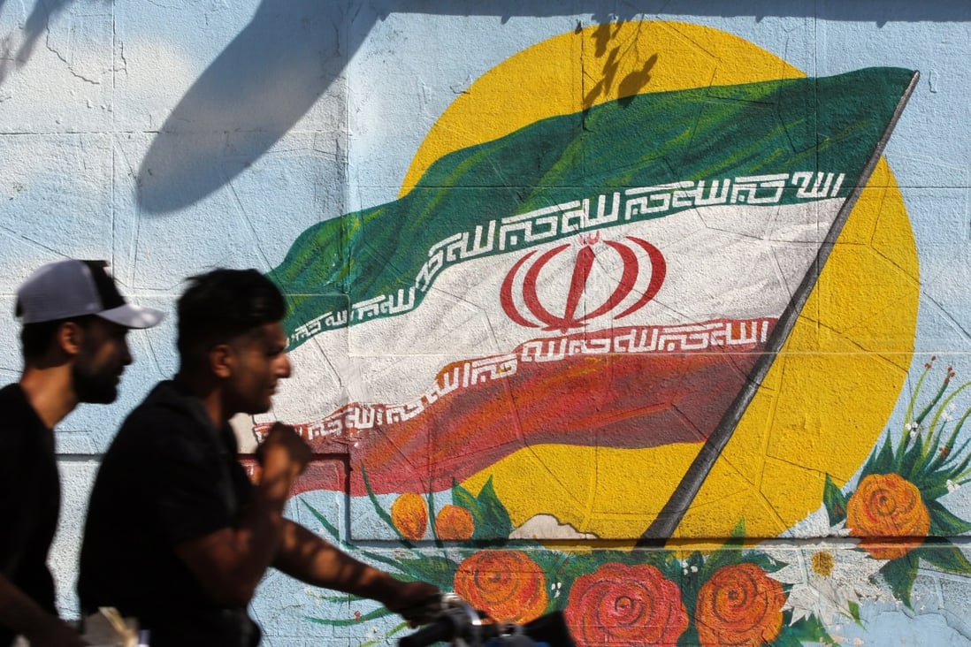 Iranians ride past painting of Iran’s flag on a wall in Tehran on Tuesday. Photo: EPA-EFE