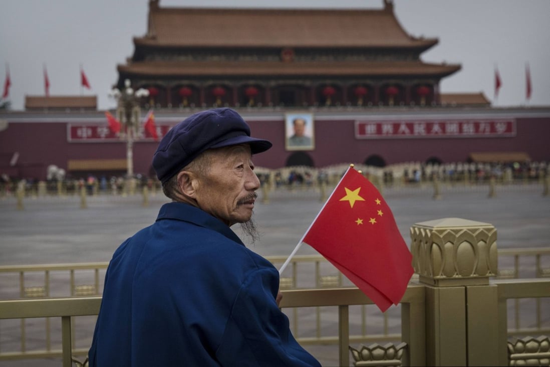 An elderly Chinese man holds a flag as he stands in Tiananmen Square on the 65th National Day on October 1, 2014 in Beijing. Photo: Getty Images