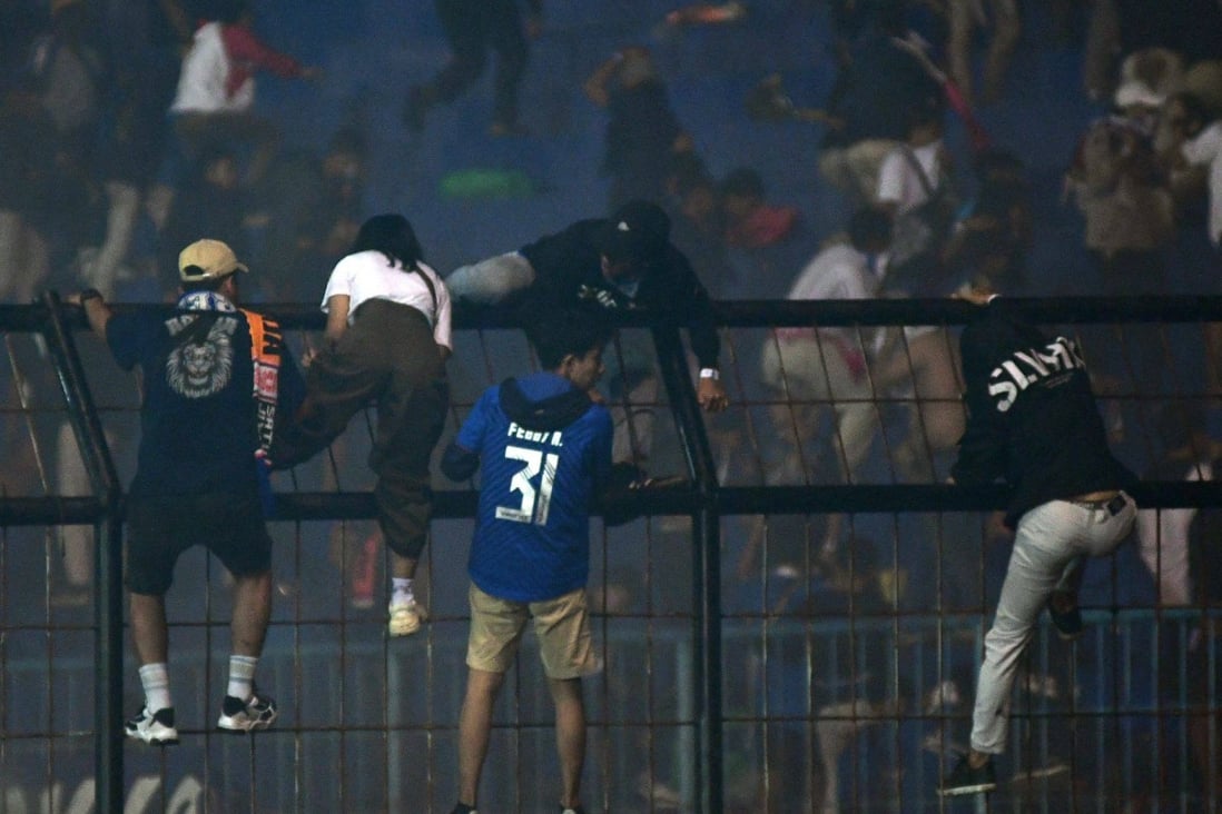Spectators climb a fence by the stands amid a deadly stampede after a football match in Indonesia. Photo: AFP/File