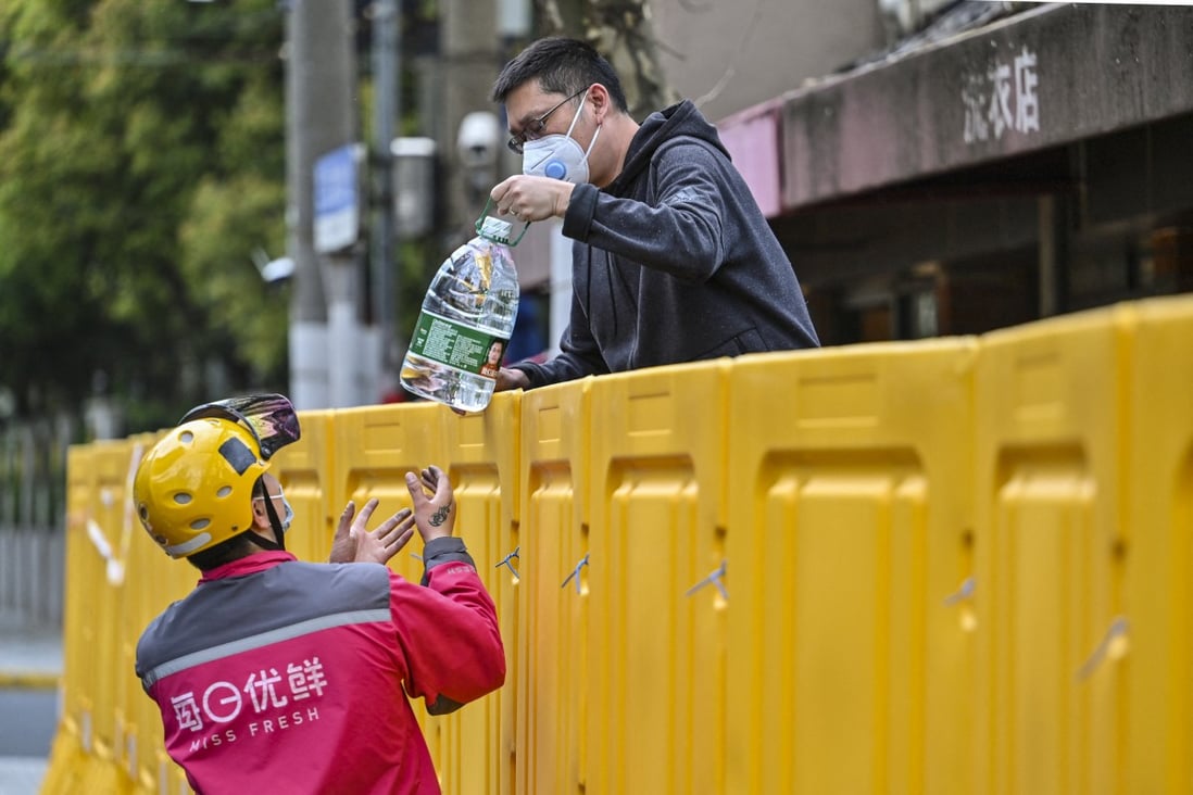 A resident receives a water delivery during Covid-19 lockdown. Panic buying of bottled water has gripped mainland China’s commercial capital, Shanghai. Photo: AFP