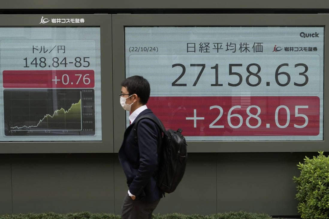 A man walks by monitors showing the Japanese yen’s exchange rate against the US dollar (left) and Japan’s Nikkei 225 index at a securities firm in Tokyo on Monday. Photo: AP