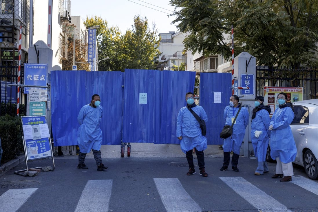 Officials in protective aprons stand outside the boarded-up gate of a residential compound placed under lockdown on Tuesday as Covid-19 outbreaks continue in Beijing. Photo: Reuters
