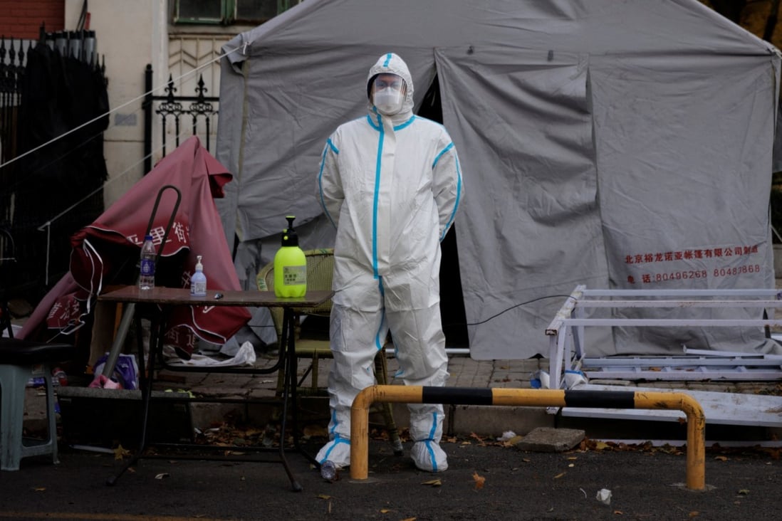 A pandemic-prevention worker stands near a locked-down apartment compound in Beijing on Saturday, a day after the State Council issued 20 measures to ease some coronavirus controls. Photo: Reuters