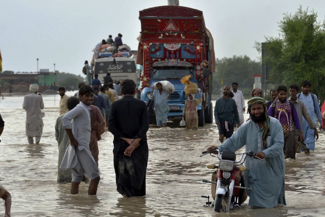People navigate through a flooded road caused by heavy monsoon rains, in Pakistan. Photo: AP/File