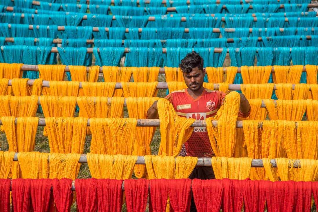 A worker in Bangladesh hangs freshly dyed cotton thread to dry in the sun this week. The country has been seeing a large increase in clothing orders from the United States. Photo: DPA