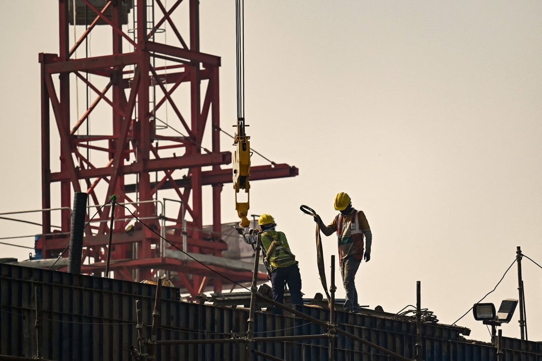 Workers stand atop scaffolding at an under-construction flyover site in New Delhi on November 21. Photo: AFP