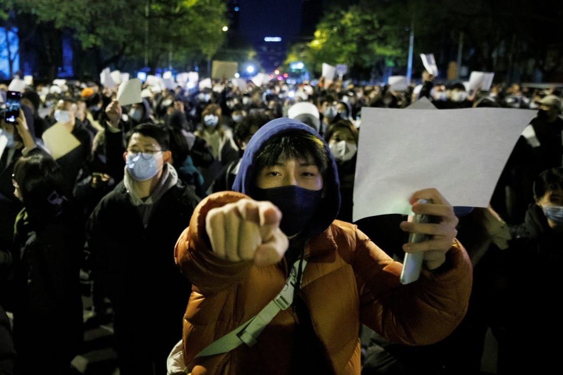 People hold white sheets of paper in protest over China’s Covid-19 restrictions after a vigil for the victims of a fire in Urumqi in Beijing on November 27. Photo: Reuters