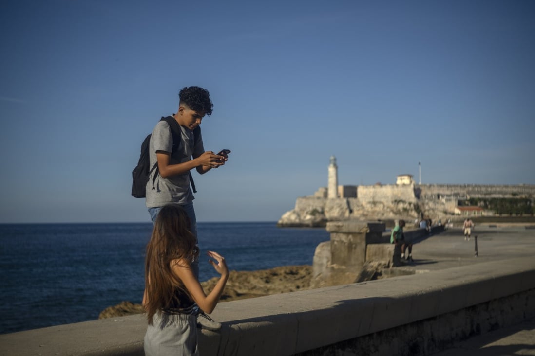 A youth uses his smartphone as he and a friend walk along the Malecon seawall in Havana, Cuba, on November 25, 2022. Ever-widening access to the internet is offering a new opportunity for Cubans looking for hard-to-obtain basic goods: online shopping. Photo: AP
