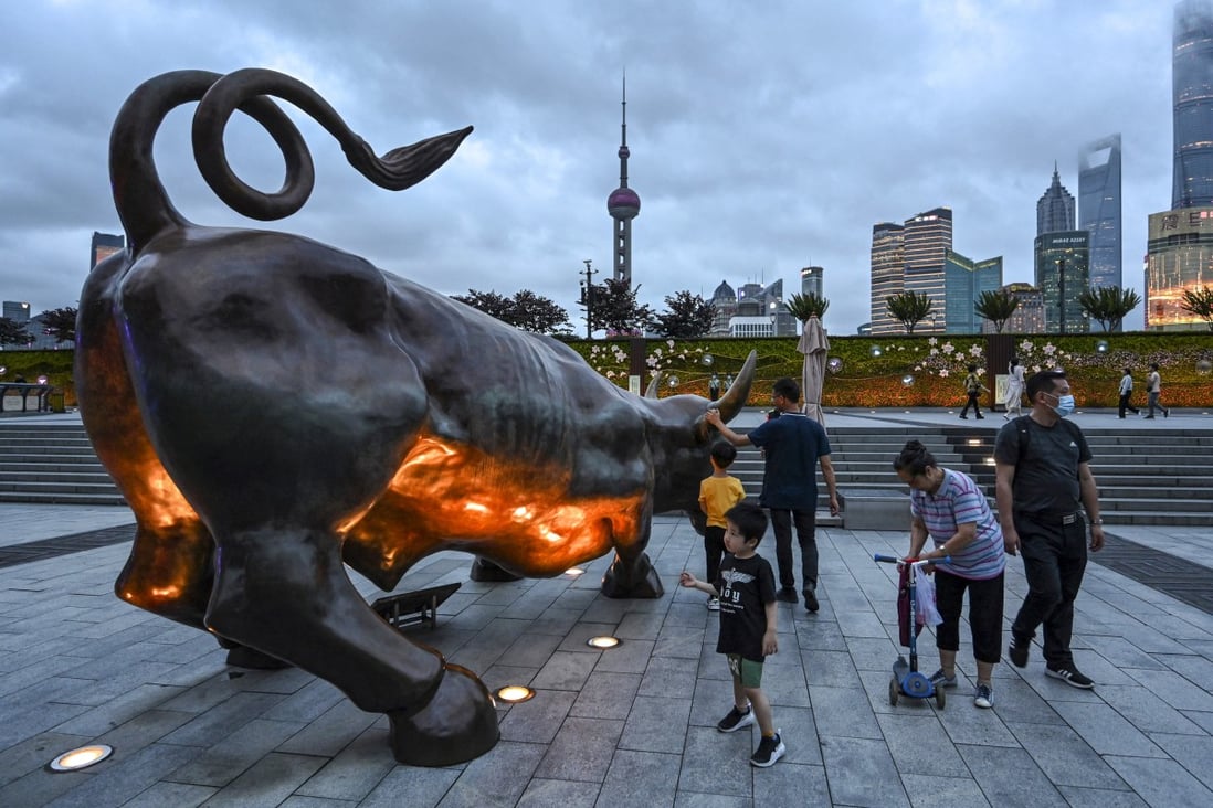 People standing next to the bull sculpture on the Bund in Shanghai. Photo: AFP
