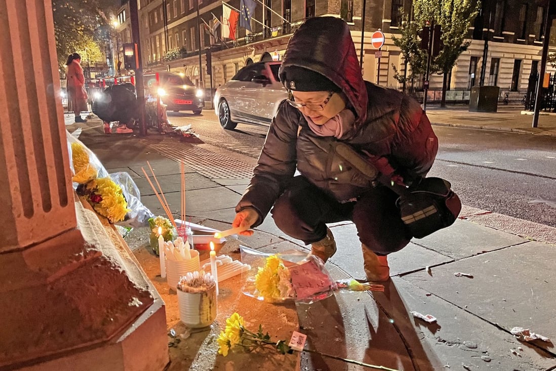 A woman lights a candle for the victims of a deadly fire in Urumqi, Xinjiang, during a solidarity protest outside the Chinese embassy in London on Monday. Photo: Kyodo