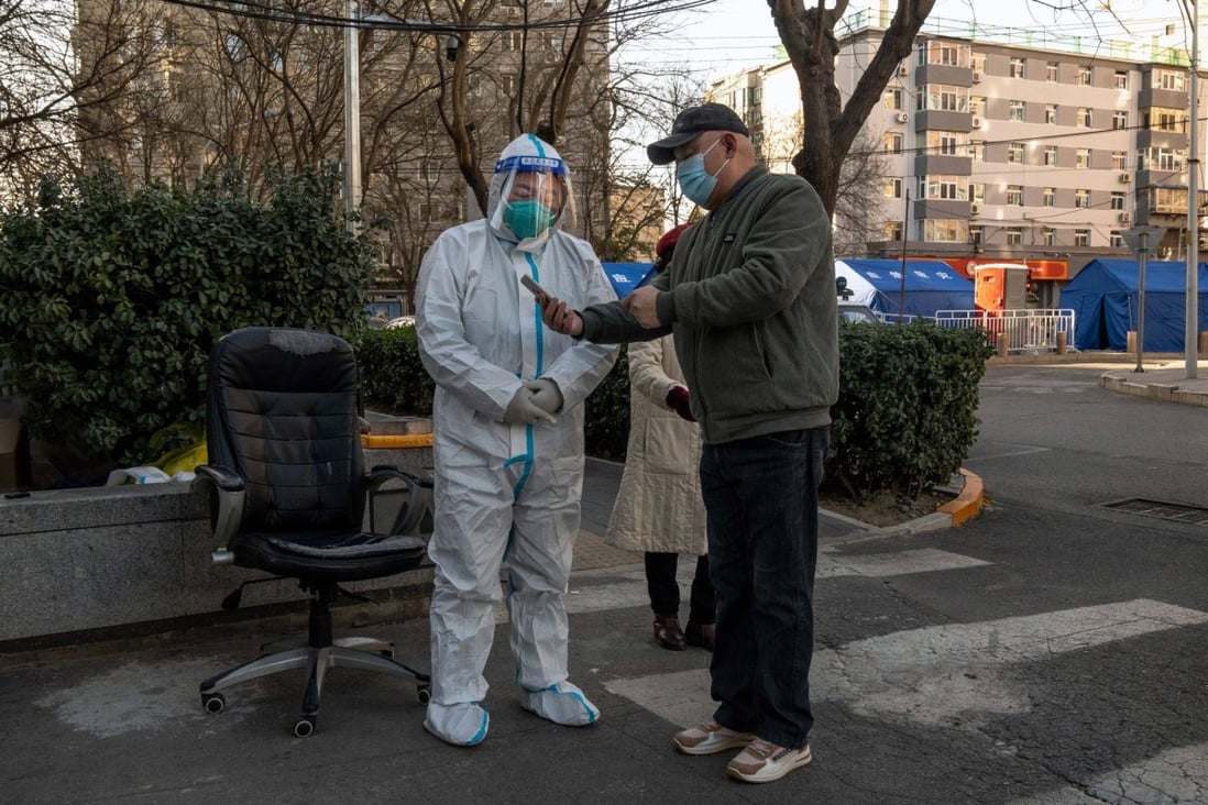 A worker in protective gear checks the health code of a resident at the gate of a neighbourhood placed under lockdown due to Covid-19 in Beijing. Photo: Bloomberg