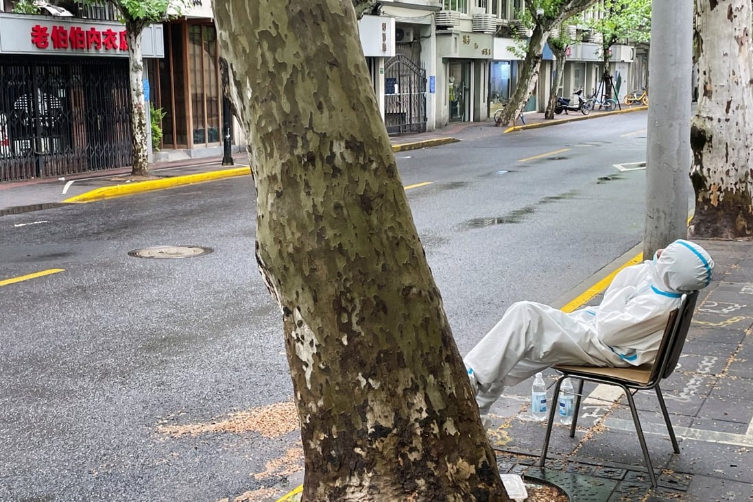 A community health worker rests by the roadside in a locked down area of Shanghai during a Covid-19 outbreak. Photo: Reuters 
