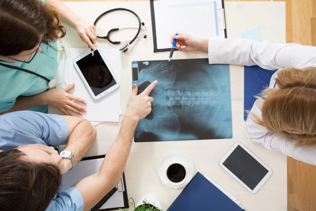 Doctors sitting around the table and interpreting x-ray image. Photo: Shutterstock/File