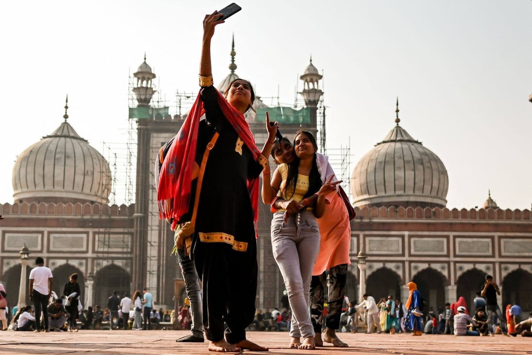 People take selfies with their phones as they visit the Jama Masjid of Delhi, one of the largest mosques in India, on November 26. India’s young population is attractive to businesses looking for new markets. Photo: AFP 