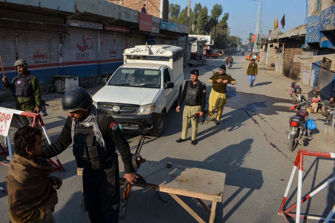 Police stand guard along a road they blocked after Taliban militants seized a police station in Bannu on December 19, 2022. Photo: AFP