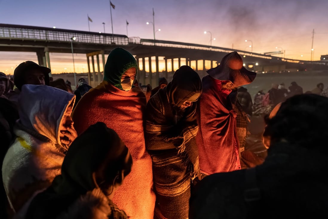 Immigrants keep warm by a fire near the US-Mexico border fence in El Paso, Texas, on Thursday. Texas Governor Greg Abbott is a strong critic of President Joe Biden on his handling of the border. Photo: TNS
