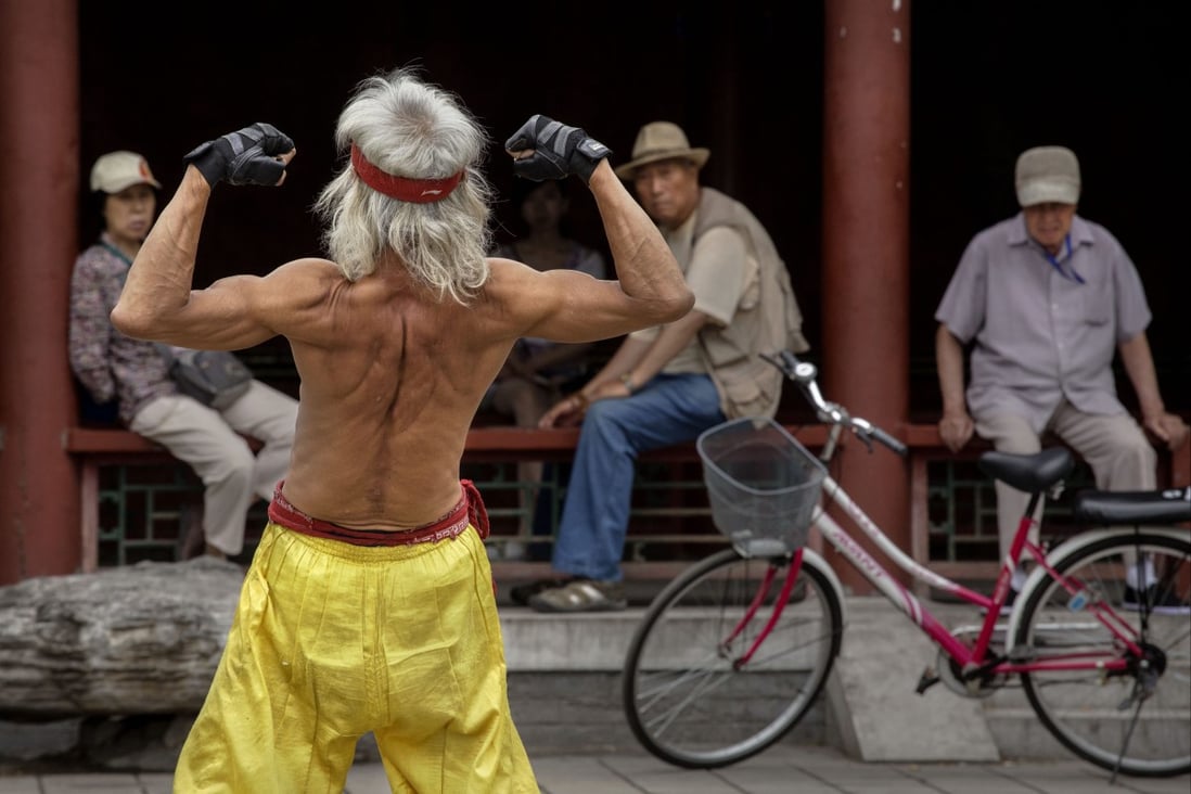 An elderly Chinese man flexes his muscles as he performs a martial arts routine on the street for onlookers in Beijing, China. Photo: Getty Images