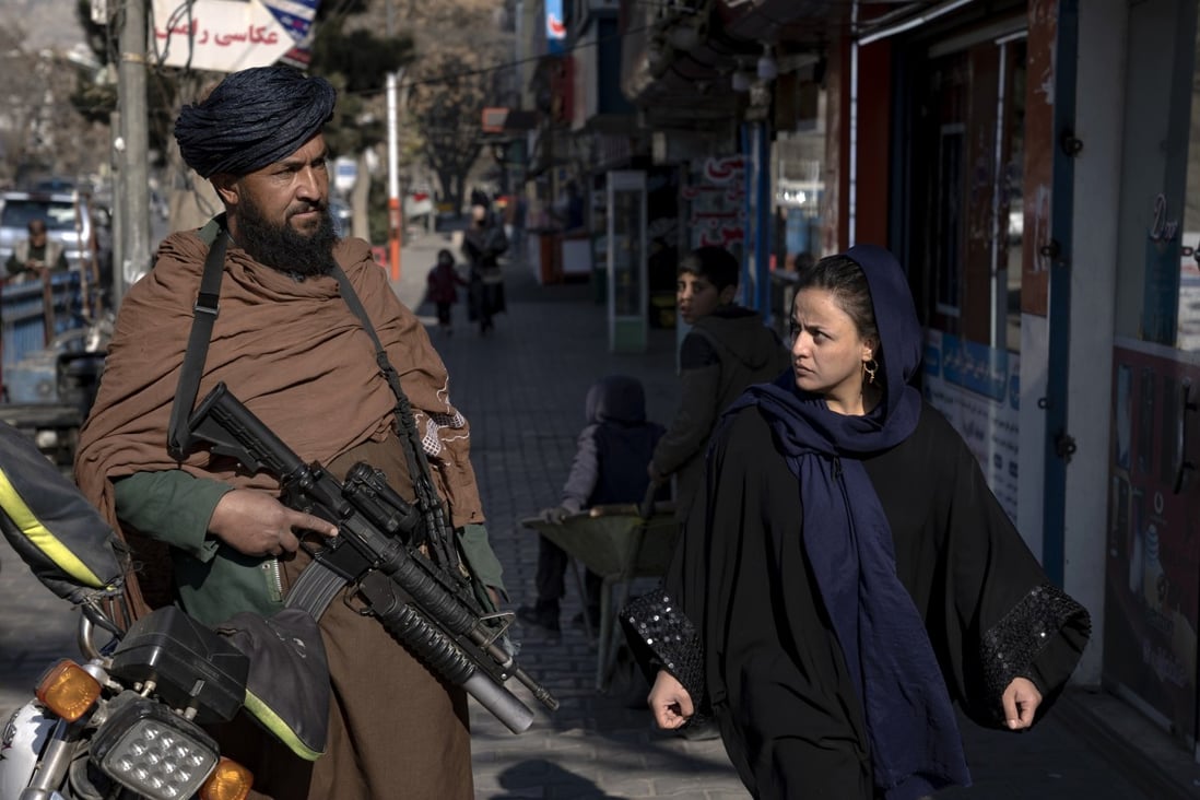 A Taliban fighter stands guard as a woman walks past in Kabul, Afghanistan. Photo: AP
