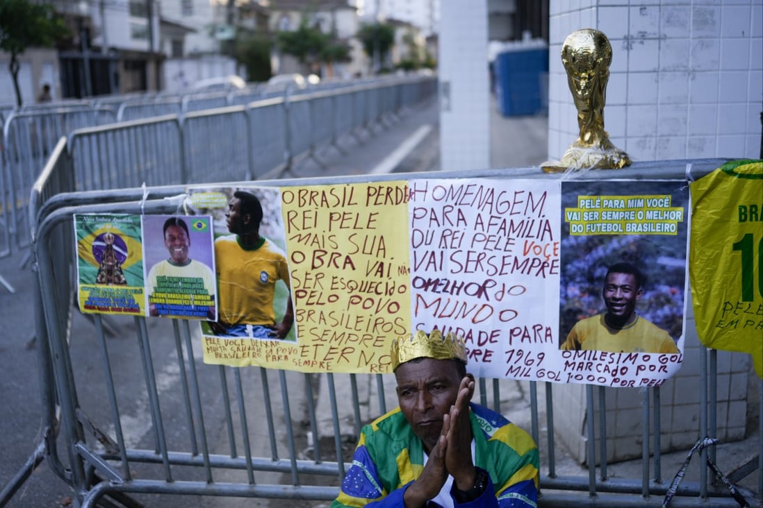 A man sits outside the Vila Belmiro stadium in Santos before the wake for Pele. Photo: AP