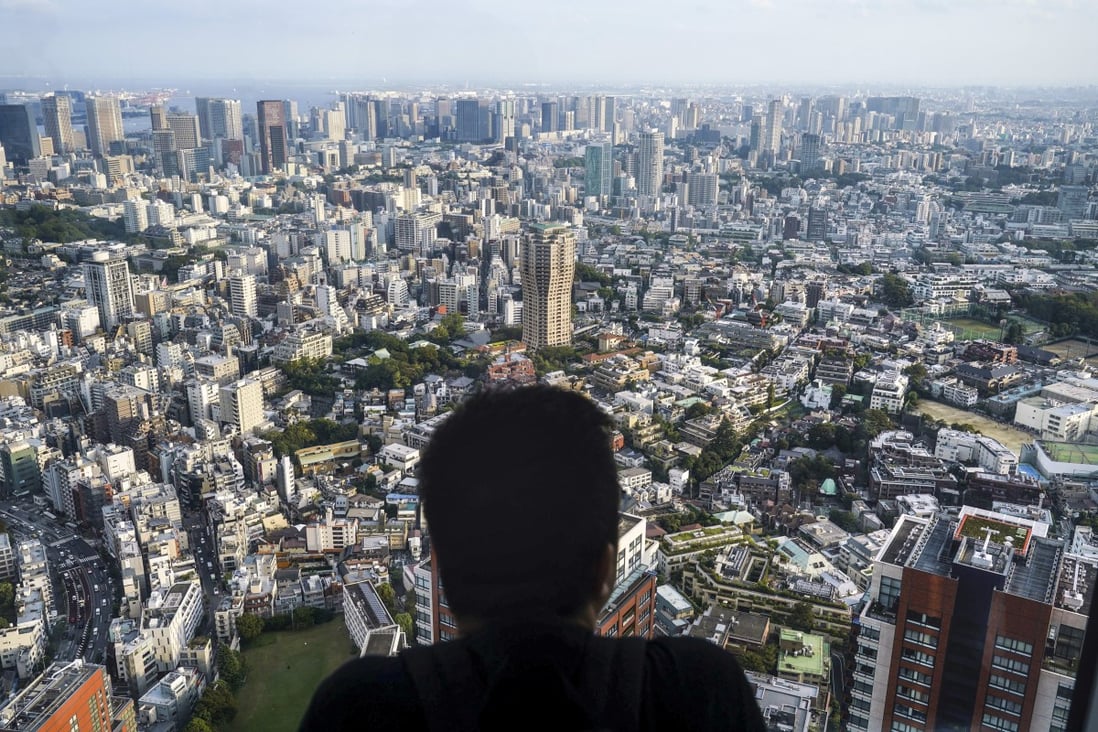 A man watches the cityscape of Tokyo from an observation deck on the top floor of Roppongi Hills Mori Tower. With the new incentives, Tokyo hopes to attract 10,000 families to move out of the city in 2027. Photo: AP