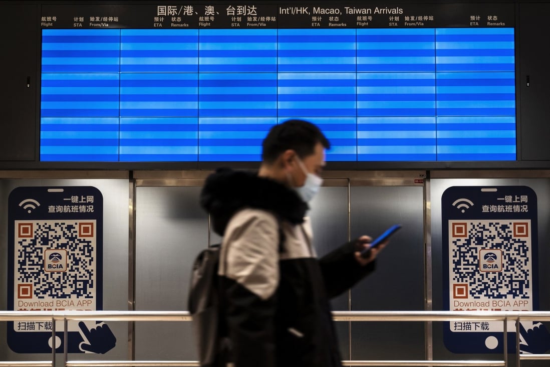 A man wears a mask as he walks by an empty screen displaying no international flights in the international arrivals area of Beijing Capital Airport on Friday. Photo: Getty Images/File