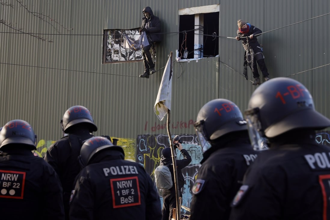 Police approach activists hanging on ropes from a building in the village of Luetzerath, Germany, where they are protesting about the reopening of a coal mine. Photo: EPA-EFE