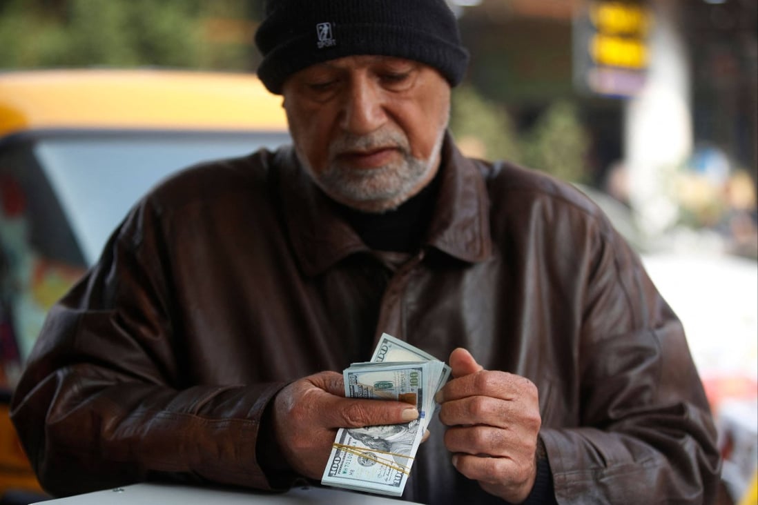 A man counts US dollar banknotes at a stock market in Baghdad in December 2022 as the value of Iraqi dinar against the US dollar drops further. Photo: AFP