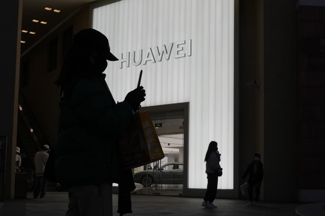 Shoppers are silhouetted outside a Huawei retail store in Beijing on December 30, 2022. Huawei says it has pulled itself out of “crisis mode” following years of US restrictions that have stifled its sales in overseas markets. Photo: AP