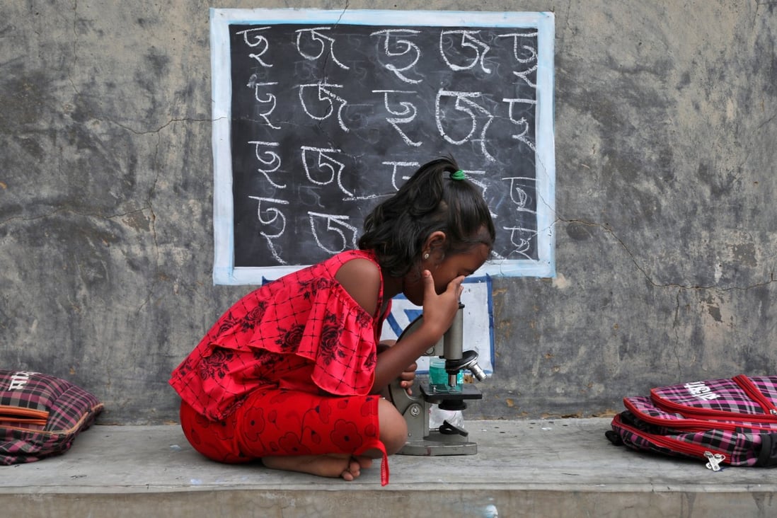 A girl with no access to internet facilities and gadgets uses a microscope as she attends an open-air class at Joba Attpara village in the Indian state of West Bengal on September 13, 2021. Ensuring women and girls have equitable access to the internet and can go online safely is an essential part of creating a inclusive and sustainable digital transformation in Asia and the Pacific. Photo: Reuters