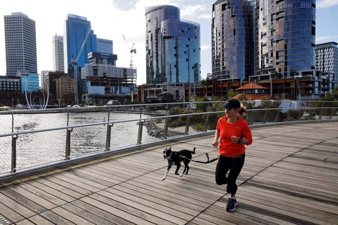 A woman runs with her dog through Elizabeth Quay in Perth, Western Australia, on June 29, 2021. Unlike those in major cities on Australia’s east coast, housing prices in Perth remain relatively affordable. Photo: AFP