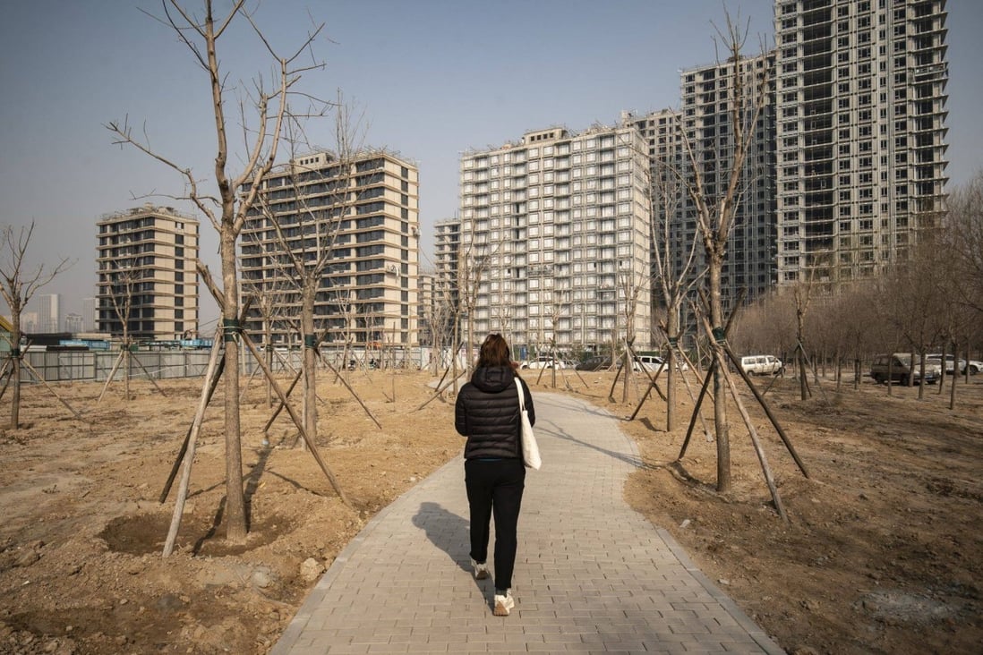 A pedestrian heads towards residential apartments under construction in Beijing on March 4. Tensions between efforts to forestall a financial crisis and the need to reduce leverage and speculation make it extremely difficult to restore confidence in the industry, particularly among homebuyers. Photo: Bloomberg 