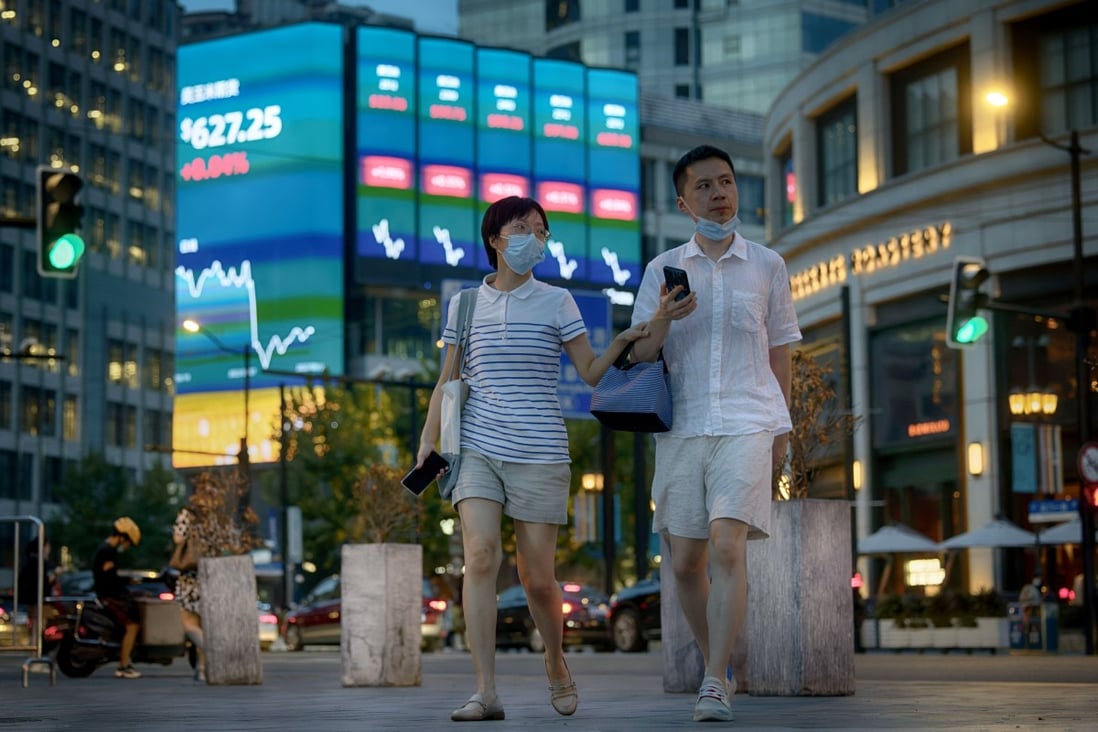 People walk in front of the large screen showing the latest stock exchange data in Shanghai in August 2022. Photo: EPA-EFE