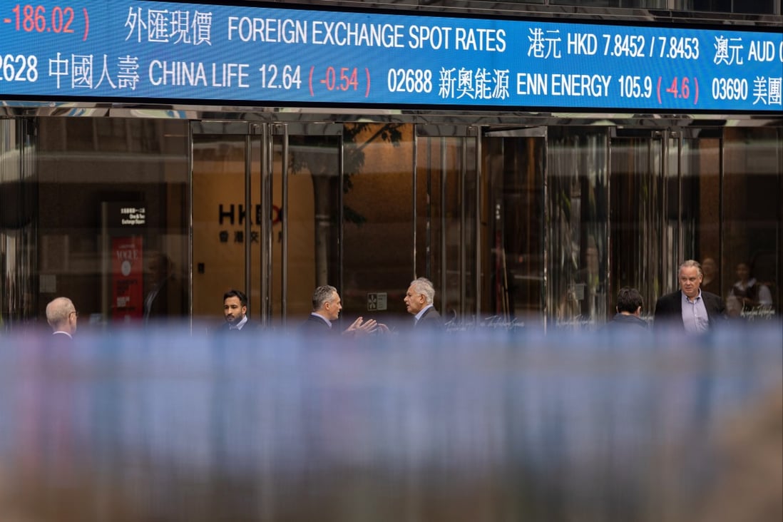 Pedestrians walk past a screen showing stock tickers outside the Exchange Square in Central, Hong Kong on March 14. Photo: EPA-EFE