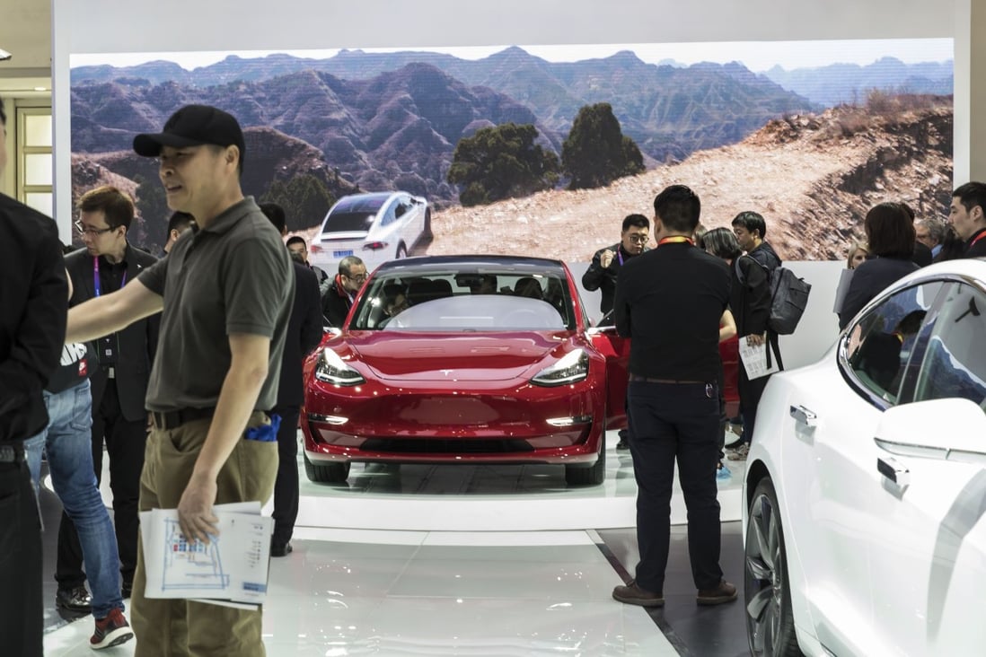 Attendees inspect a Tesla Model 3 vehicle, centre, as it stands on display at the Beijing International Automotive Exhibition on April 25, 2018. Photo: Bloomberg