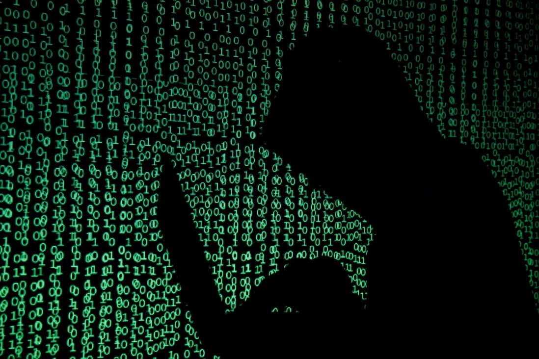 A hooded man holds a laptop computer as cyber code is projected on him in this illustration picture. Photo: Reuters