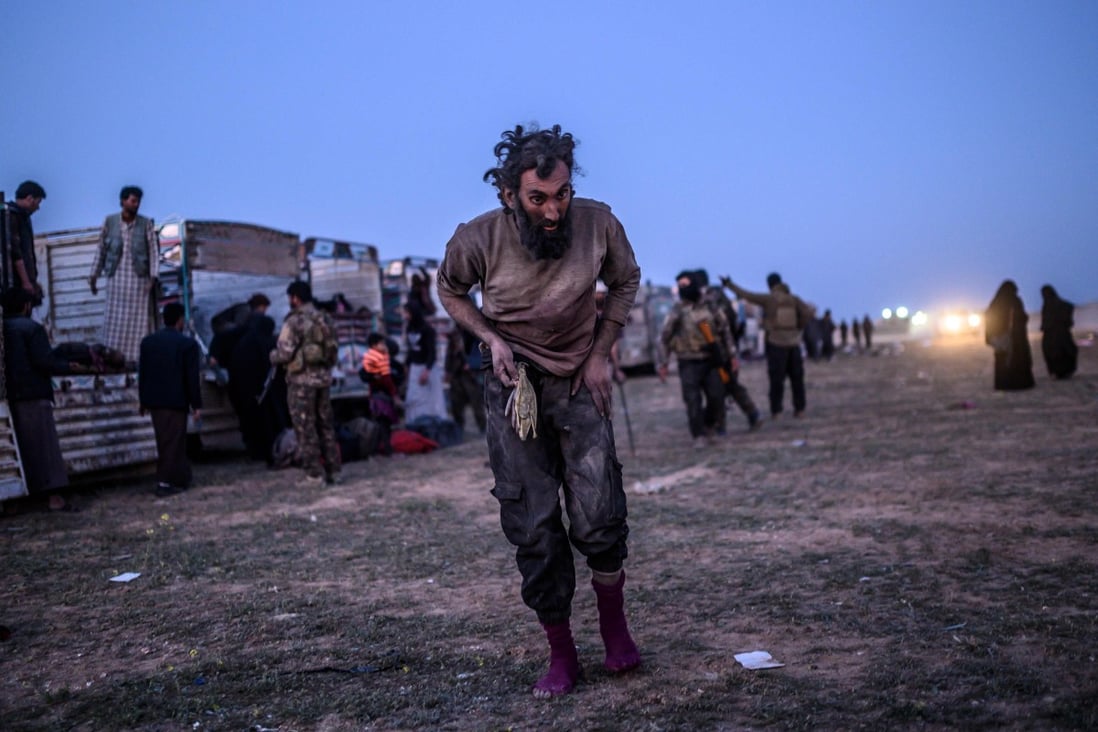 A man suspected of belonging to Islamic State walks past members of the Kurdish-led Syrian Democratic Forces (SDF) just after leaving IS' last holdout of Baghouz. Photo: AFP