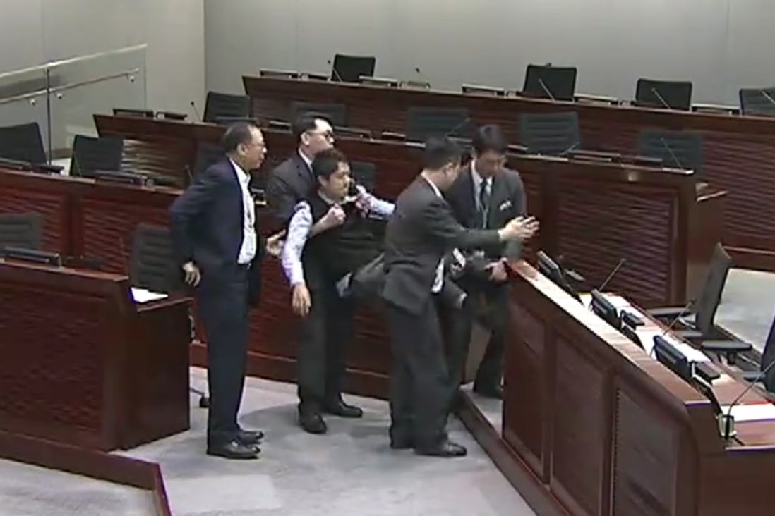 Security guards carry lawmaker Ted Hui from the meeting room on Monday. Photo: TVB