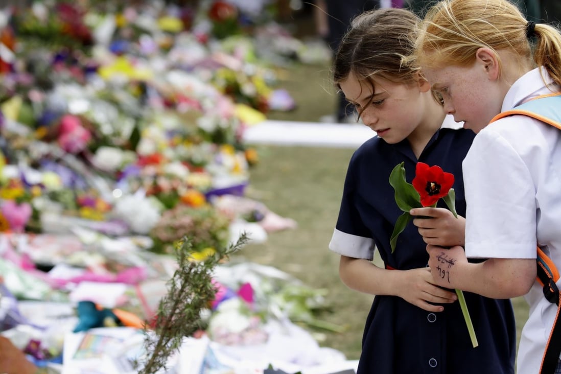 Children offer flowers on March 21 at a memorial site in Christchurch, New Zealand, for the 50 people who died in a gun attack on two mosques last week. In his online “manifesto”, the alleged gunman showed support for white supremacist and anti-Muslim, anti-Jewish, anti-immigrant ideology, as well as admiration for “non-diverse” nations. Photo: Kyodo