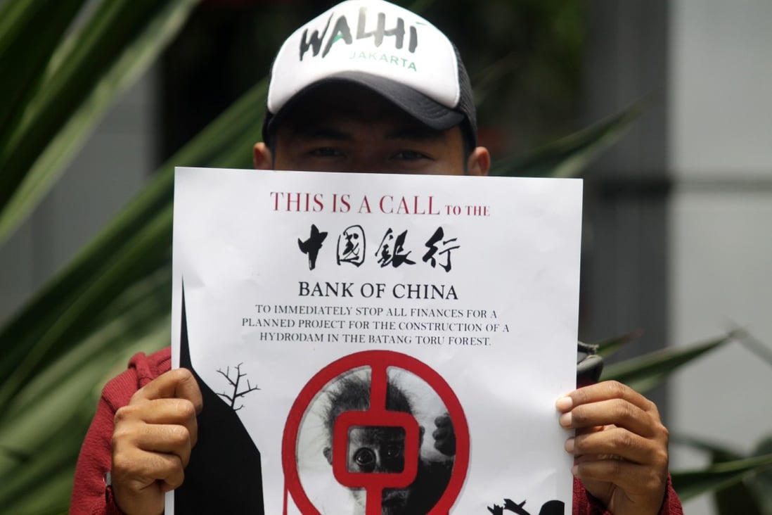 An environmental activist holds up a poster protesting against Bank of China’s funding of the construction of the Batang Toru hydroelectric power plant in the Batang Toru forest, North Sumatra, Indonesia. Photo: Aditya Irawan