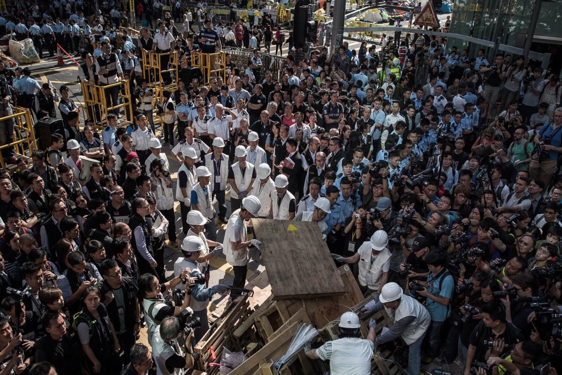 Workers assist bailiffs in removing a barricade under a court injunction in Mong Kok on November 25, 2014. Photo: AFP