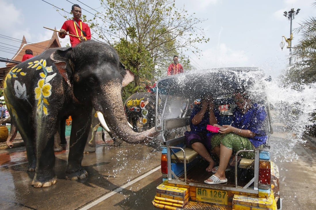 A Thai mahout rides on an elephant spraying water on revellers. Photo: EPA