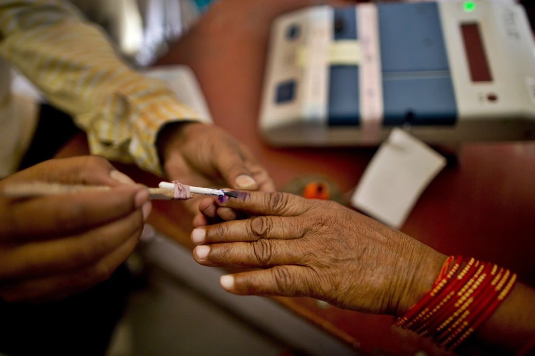 A polling officer puts an indelible ink mark on the index finger of an elderly voter at a polling station in Uttar Pradesh. Photo: AP