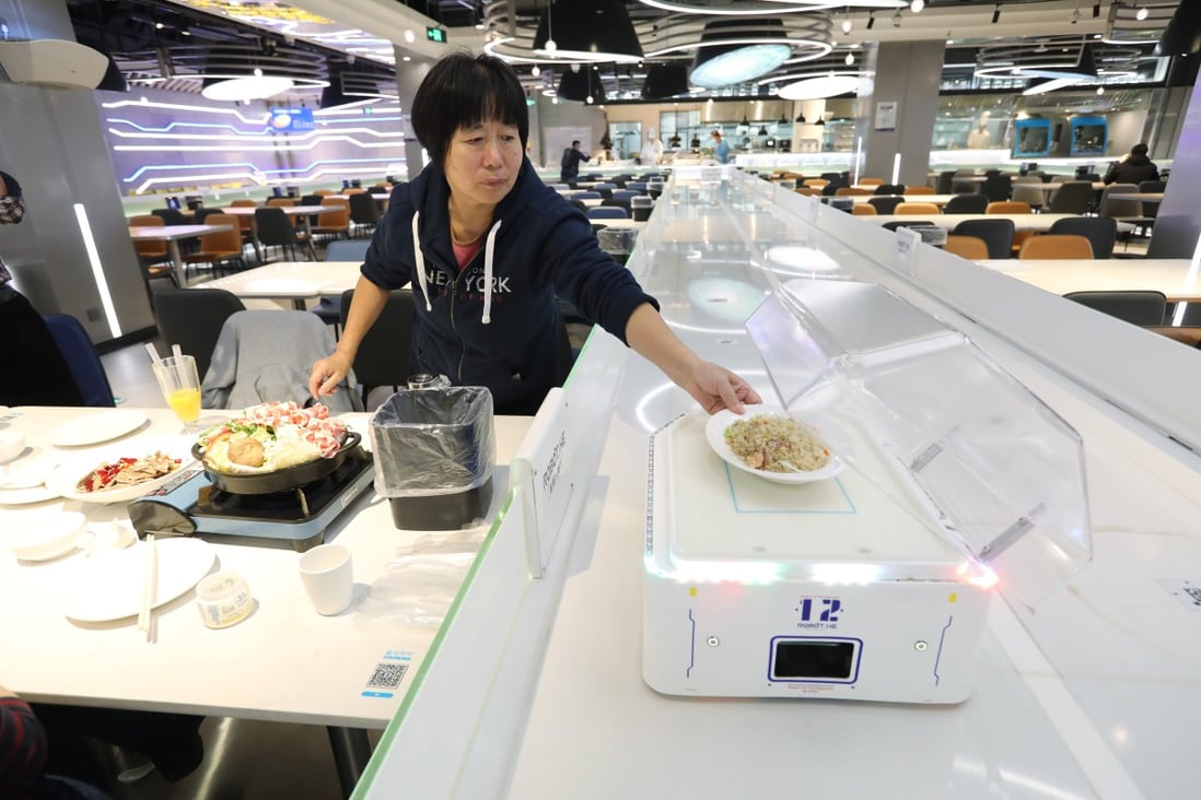 A diner at a Hema restaurant in Shanghai takes her dish after it is delivered by a robot. Photo: Simon Song