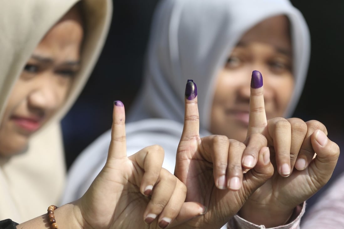 Muslim women show their ink-stained fingers after voting in Jakarta. Photo: AP
