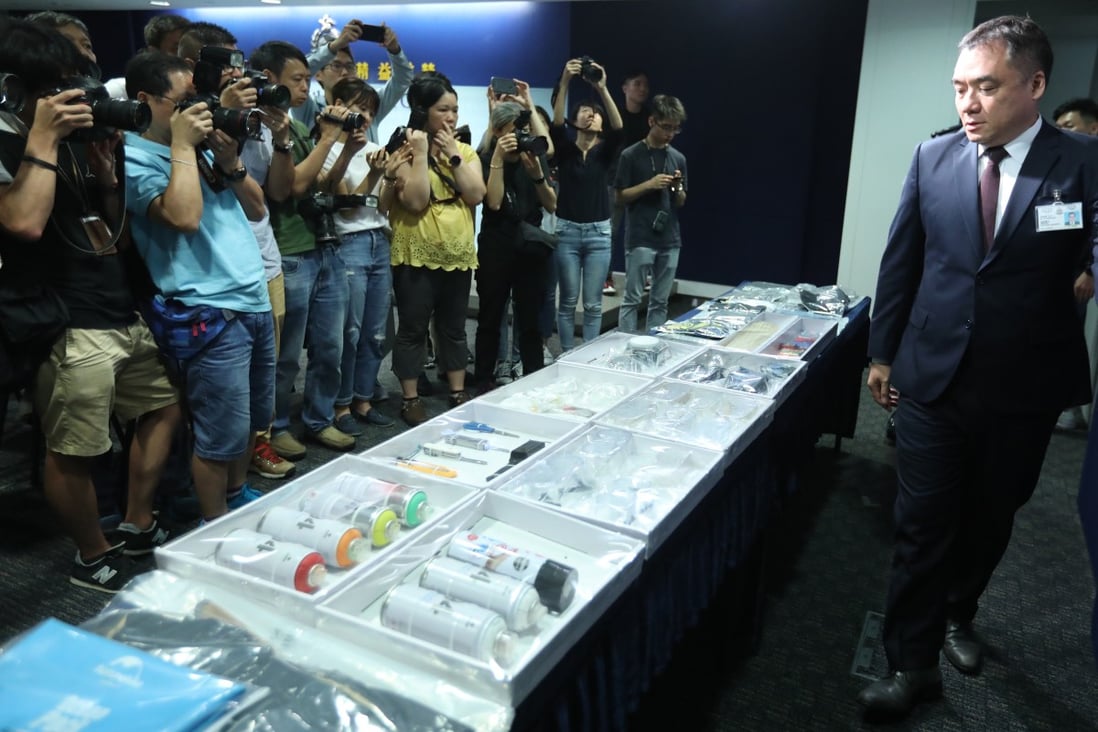 Lee Kwai-wah, the senior superintendent of the Organised Crime and Triad Bureau, examines confiscated items from protesters at police headquarters on Monday. Photo: Nora Tam