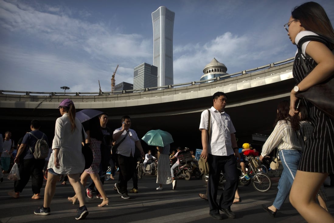 People cross the street in a crosswalk in the central business district in Beijing, Friday, May 24, 2019. (AP Photo/Mark Schiefelbein)